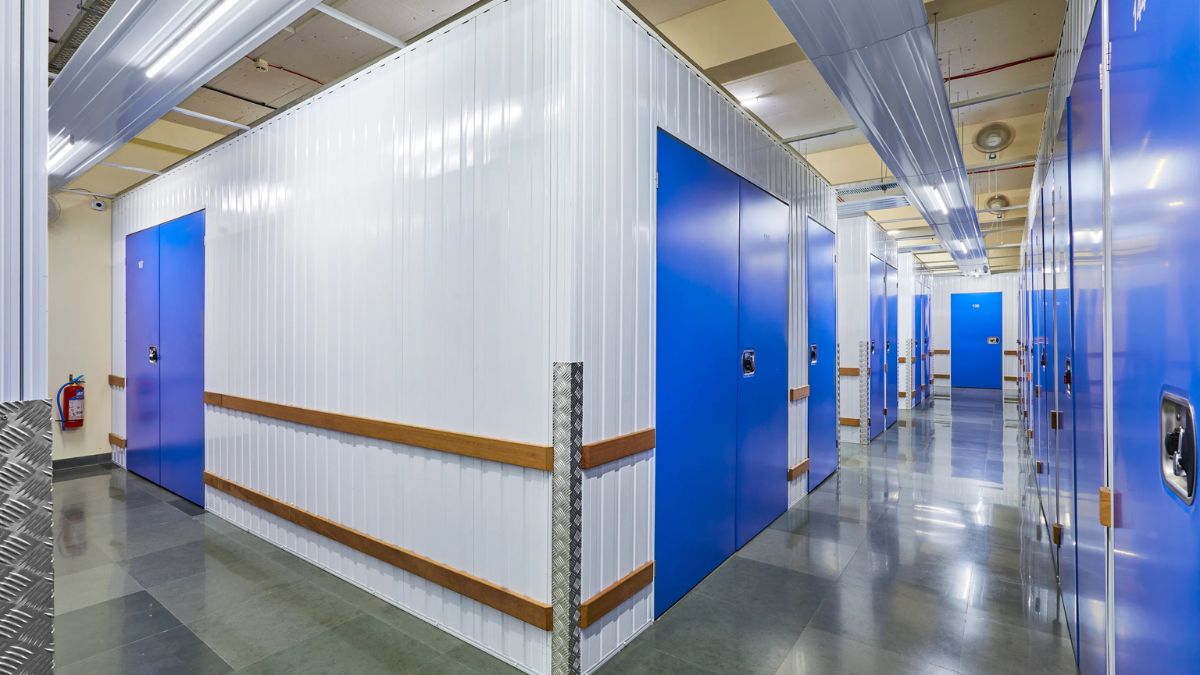 Clean corridor of a self-storage facility with blue doors and white storage units.