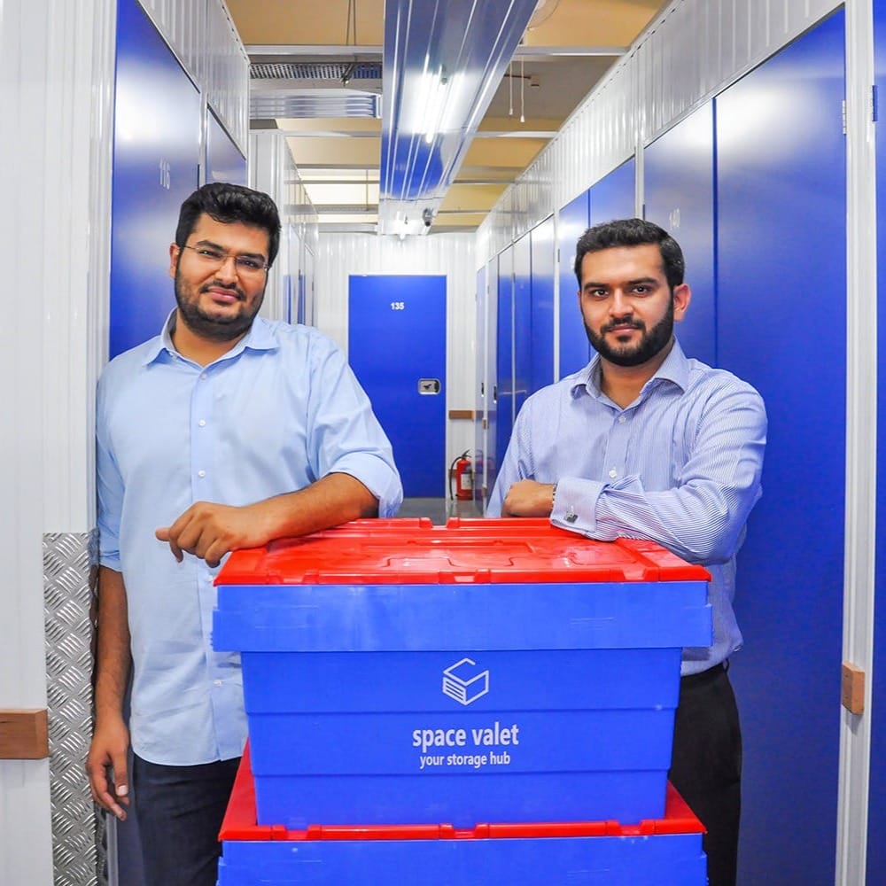 Space Valet storage container in warehouse corridor with two staff representing modern storage services.