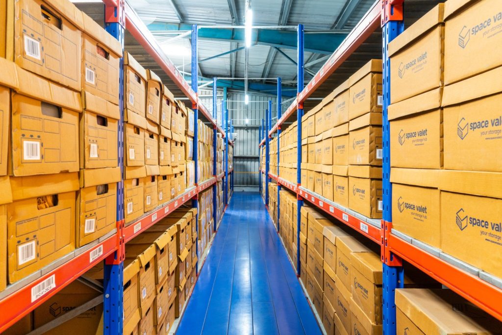 Organized storage container system with labeled boxes in warehouse shelving for bulk inventory handling.